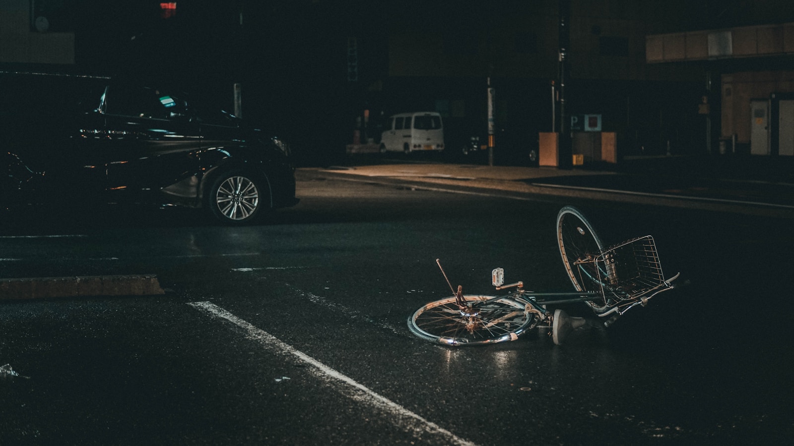 grey bicycle on road near black vehicle at nighttime